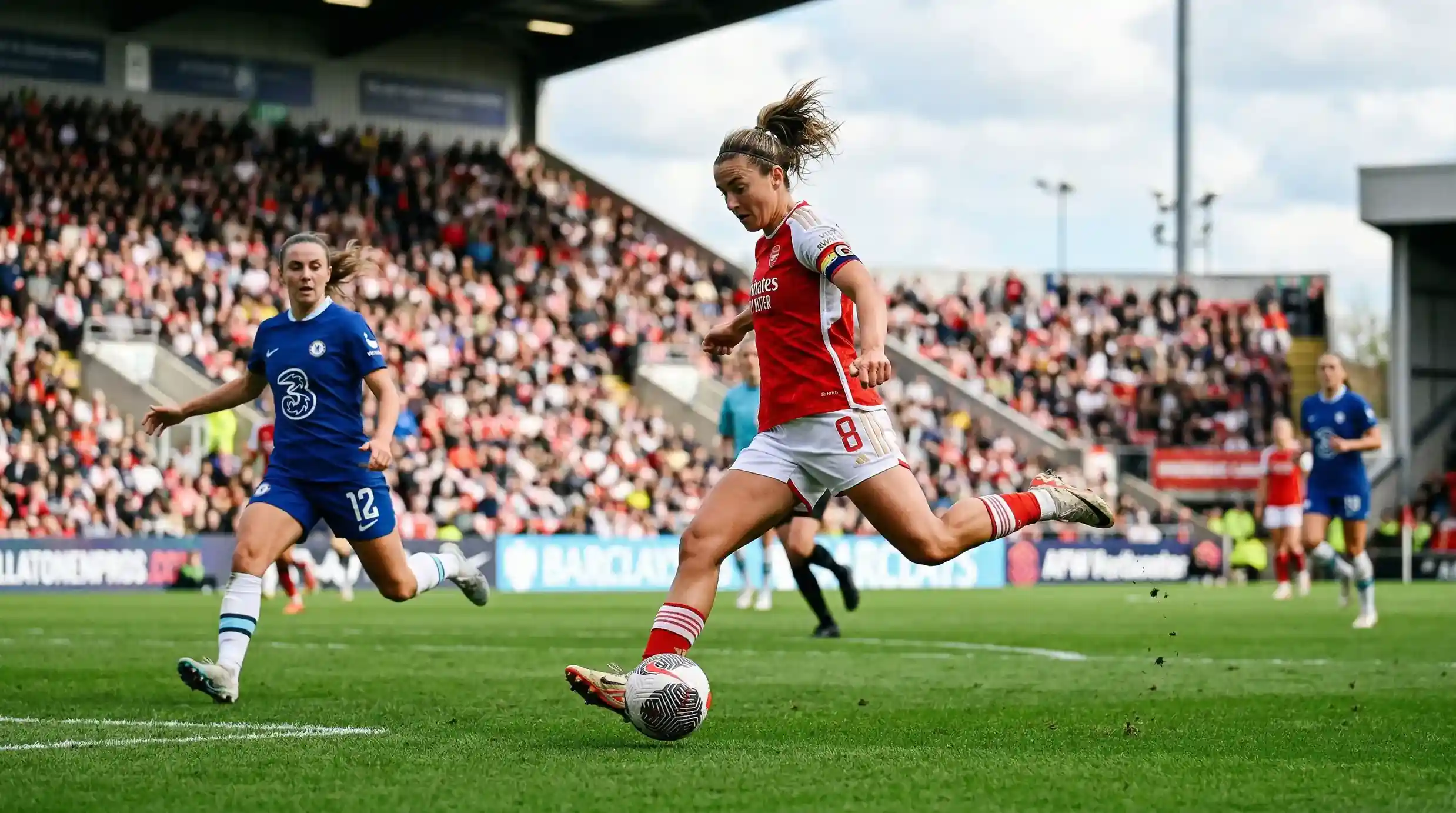 Jogadora de futebol feminino a rematar a bola num estádio com bancadas ao fundo